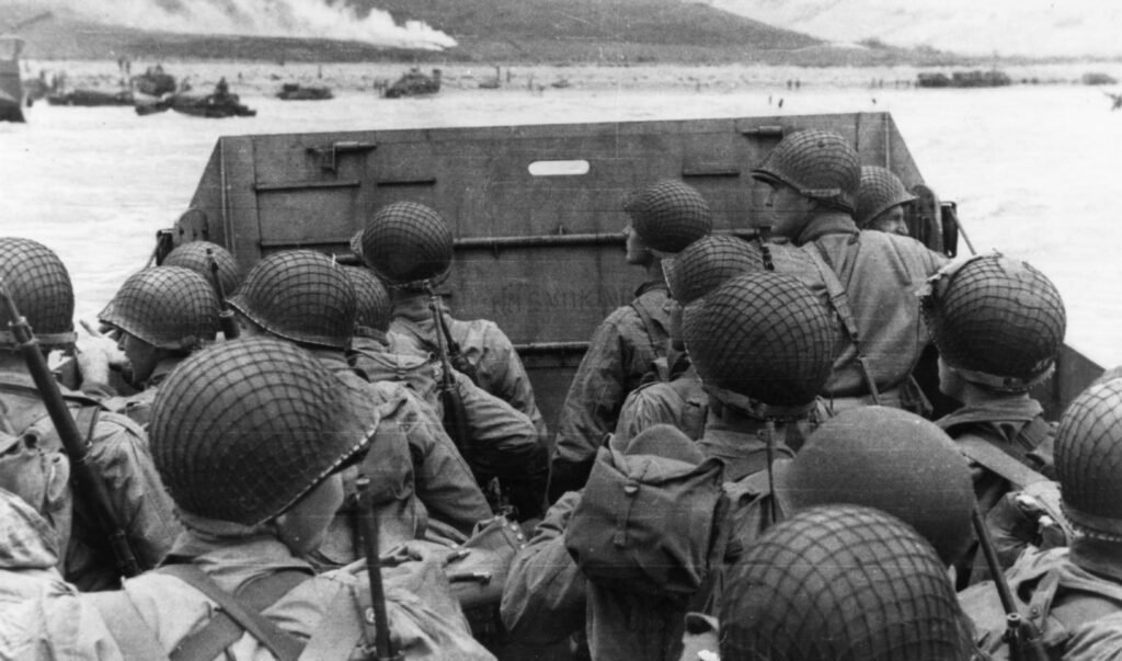 Troops in an LCVP landing craft approaching Omaha Beach on D-Day, 6 June 1944. Note helmet netting; faint No Smoking sign on the LCVP's ramp; and M1903 rifles and M1 carbines carried by some of these men. This photograph was taken from the same LCVP as Photo # SC 189986. Photograph from the Army Signal Corps Collection in the U.S. National Archives.